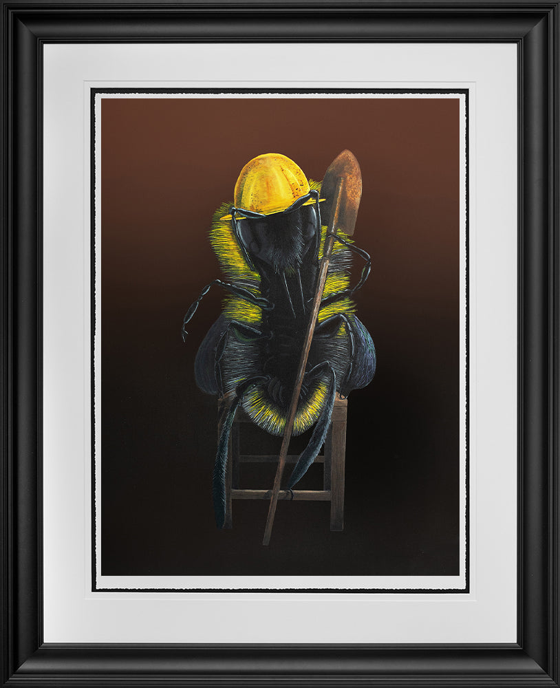Come The Revolution framed print shows a worker bee wearing a yellow hard hat and holding a shovel. The worker bee is sitting on a wooden stool. Artwork by Angus Gardner and available at The Acorn Gallery, Pocklington.