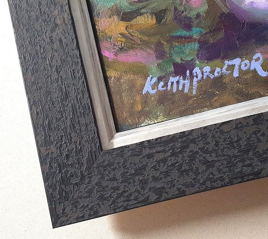 Close-up of a framed painting showing a textured dark charcoal frame, a silver inner border, and part of the colorful painted canvas with a visible artist signature.