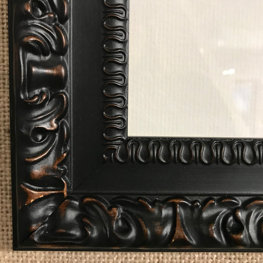 Close-up of ornate black carved frame for Shaun Tymon's original carbon pencil artwork "Stealing A Moment"