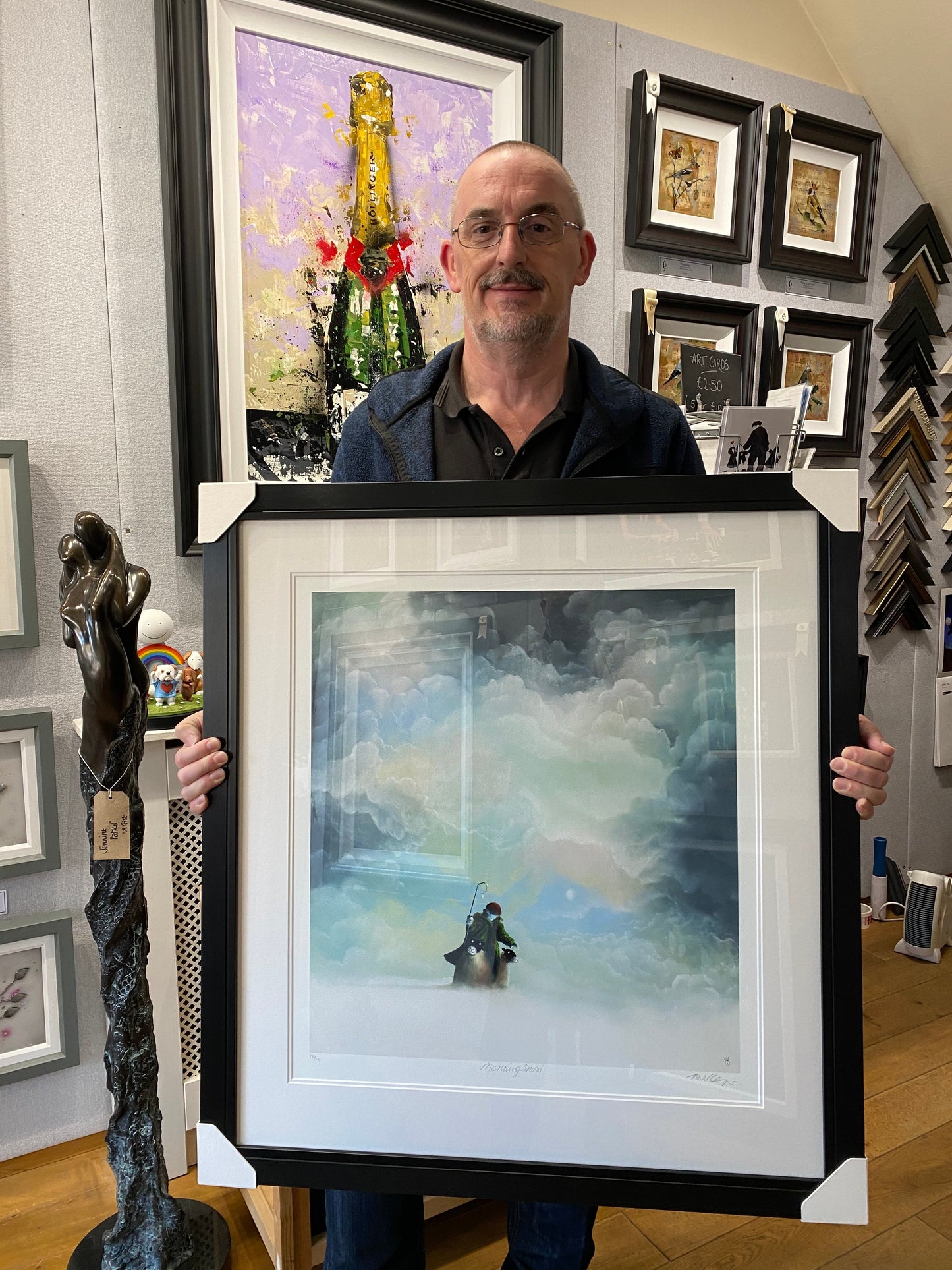 Man holding framed "Morning Snow" limited edition print by Mackenzie Thorpe in art gallery