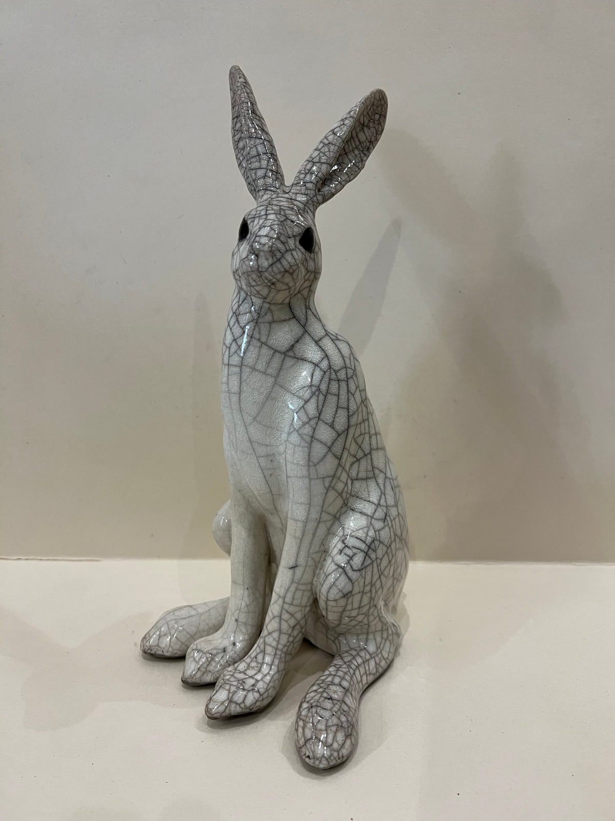 Medium Sitting Hare Raku Sculpture by Paul Jenkins, a white ceramic hare with a dark crackle glaze and upright ears.