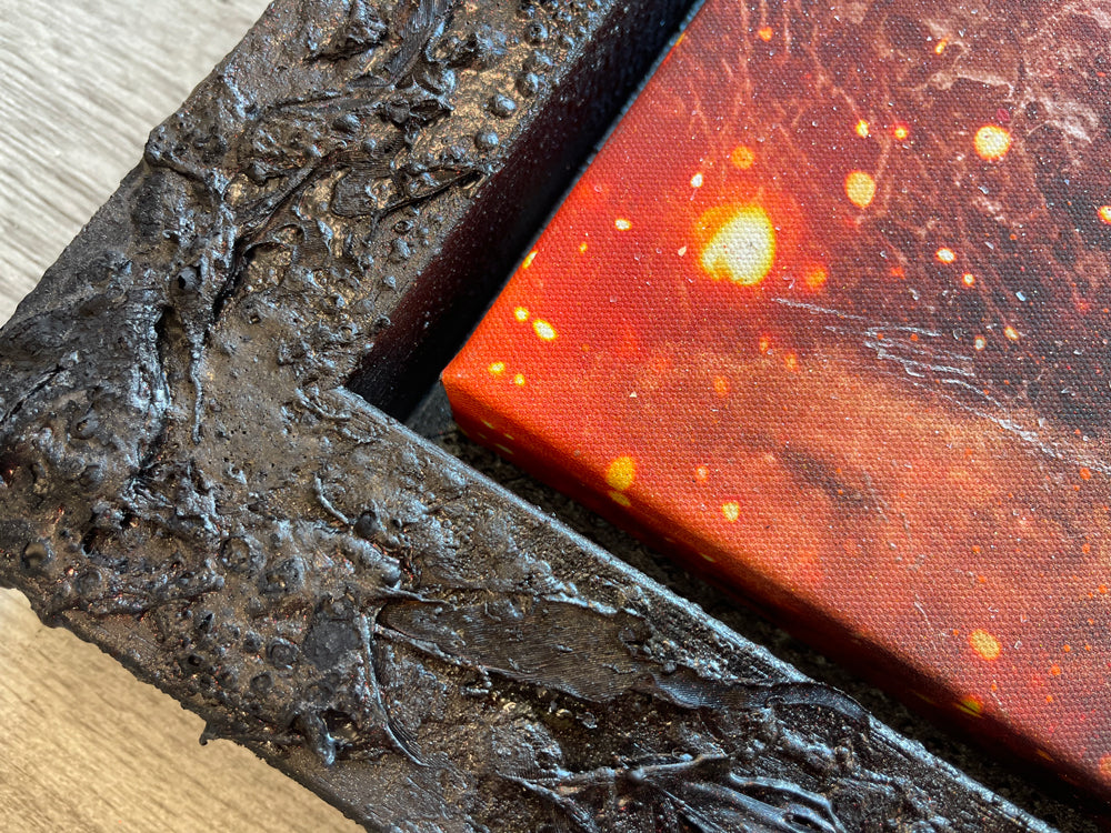Mixed media canvas artwork by Mark Davies, depicting a fiery cavern with a moonlit sky, chandelier and vivid green accents, in a dark ornate frame.