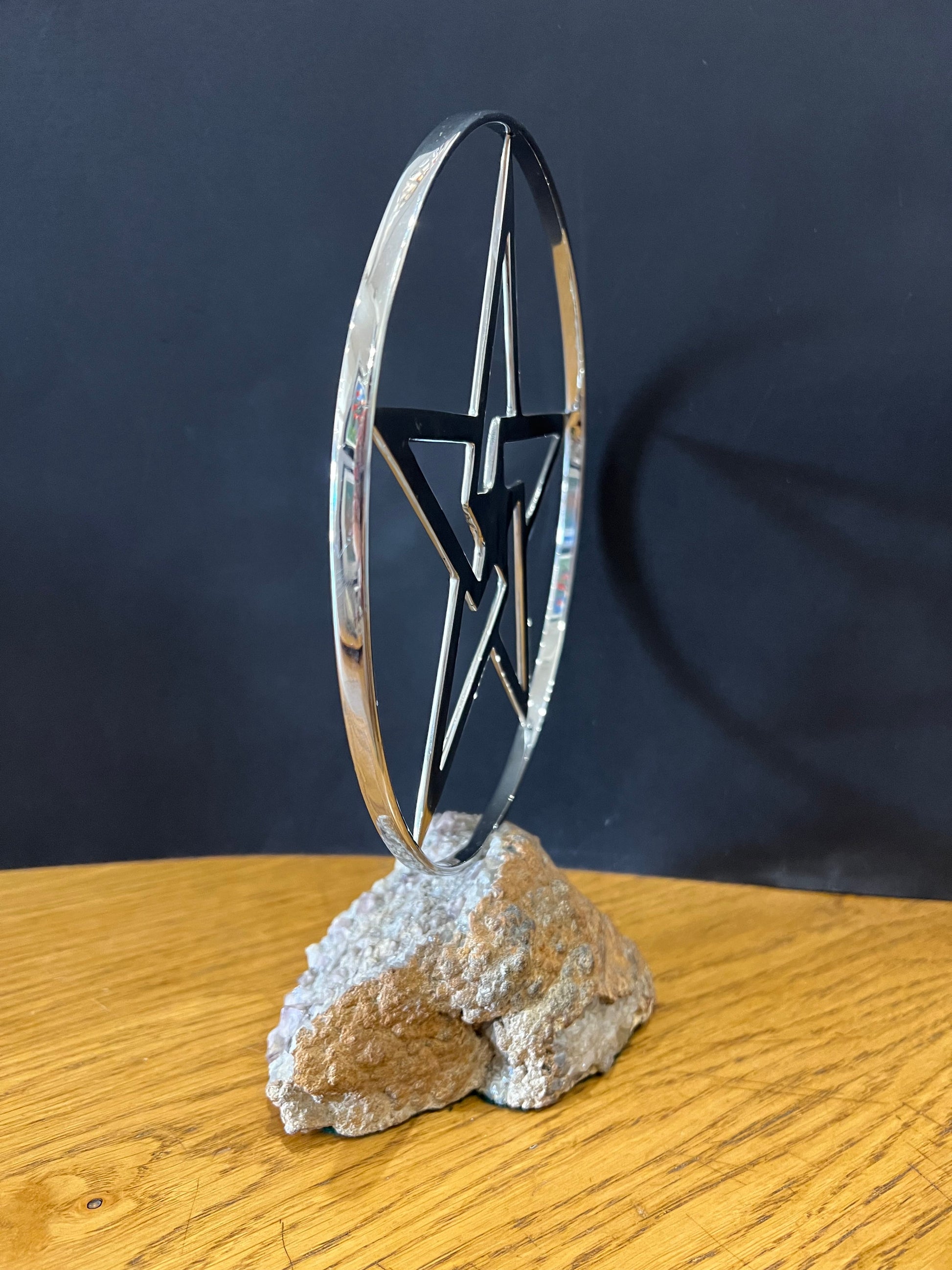 Stainless steel star in a stainless steel ring mounted on a fine looking piece of rock. Sculpture by Lancastrian sculptor Malcolm Hull and available at The Acorn Gallery in Pocklington. Call 01759 307652.