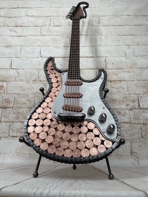 Heads and Tails metal guitar sculpture by Paul Southwell, inspired by a Fender Stratocaster and featuring British 1p and 2p coins
