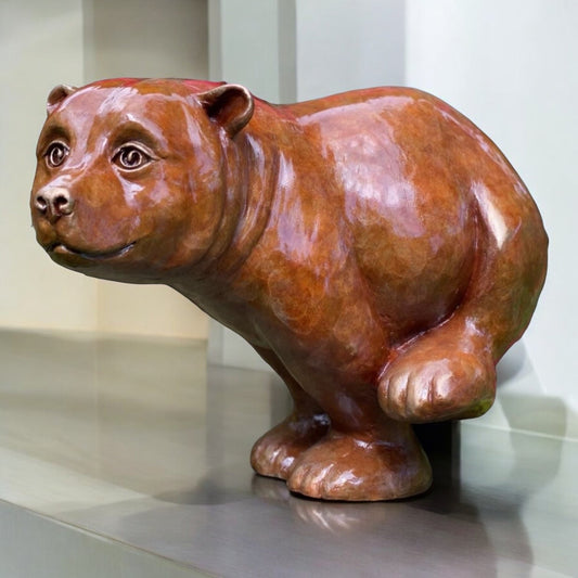 Bear sculpture by Roxy Winterburn in polished bronze with warm reddish-brown tones, rounded features and a playful running pose.