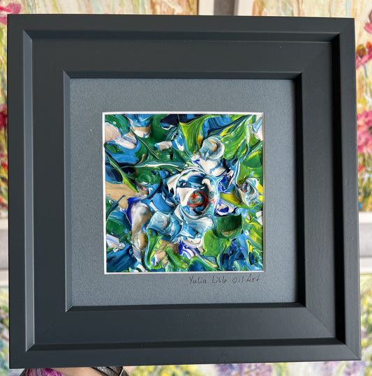 Small freestanding framed original impasto oil painting by Yulia Lisle featuring an abstract blue and white flower with vibrant green foliage, richly textured with thick palette knife strokes. Art work by Yulia Lisle and available at The Acorn Gallery in Pocklington. Shop online or call us on 01759 307652. 