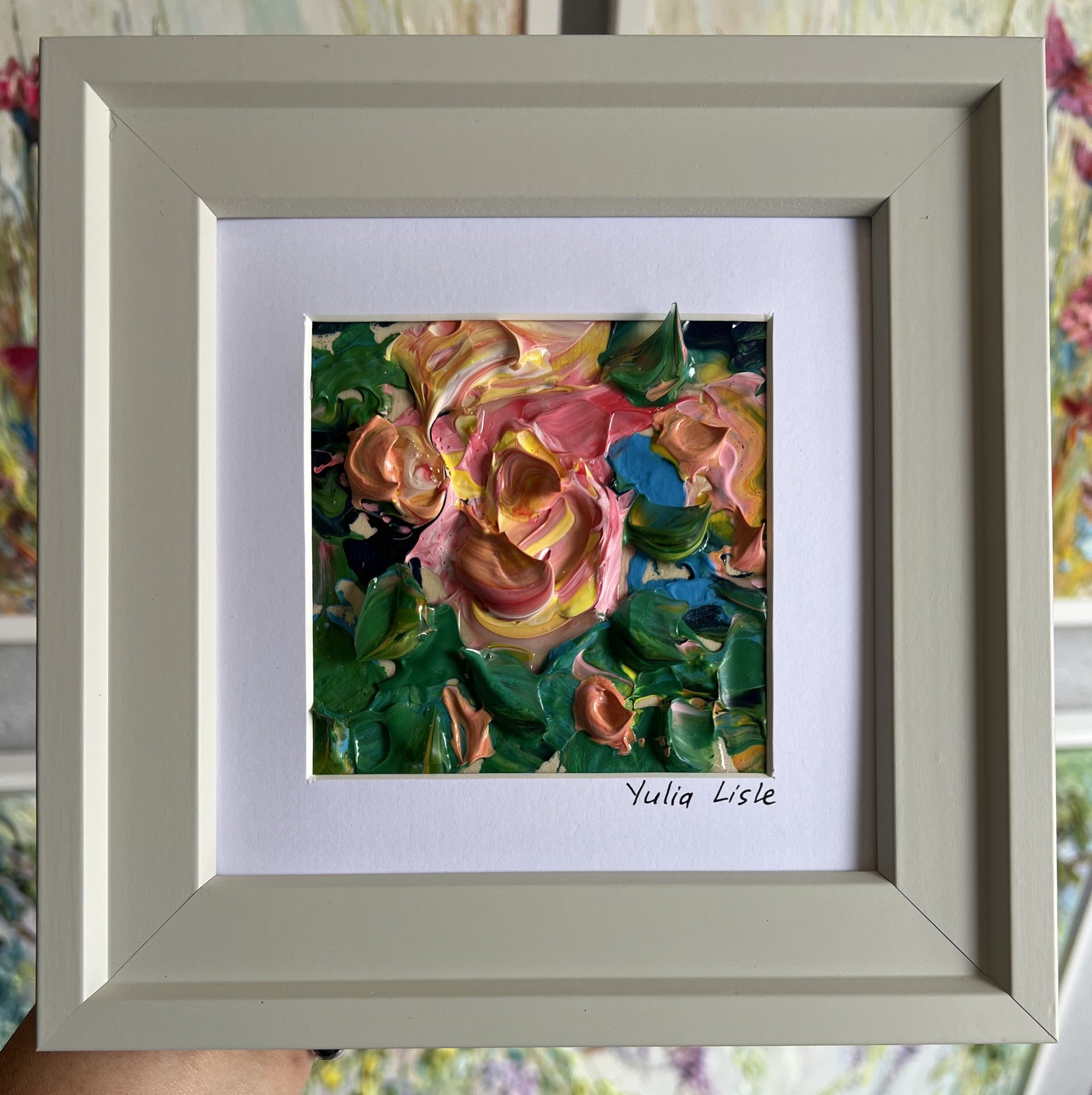 Small framed original impasto oil painting by Yulia Lisle featuring a softly textured pink flower surrounded by lush green foliage, painted with expressive palette knife strokes and rich layers of oil paint. Artwork by Yulia Lisle and available at The Acorn Gallery in Pocklington where you can shop online or call us on 01759 307652.