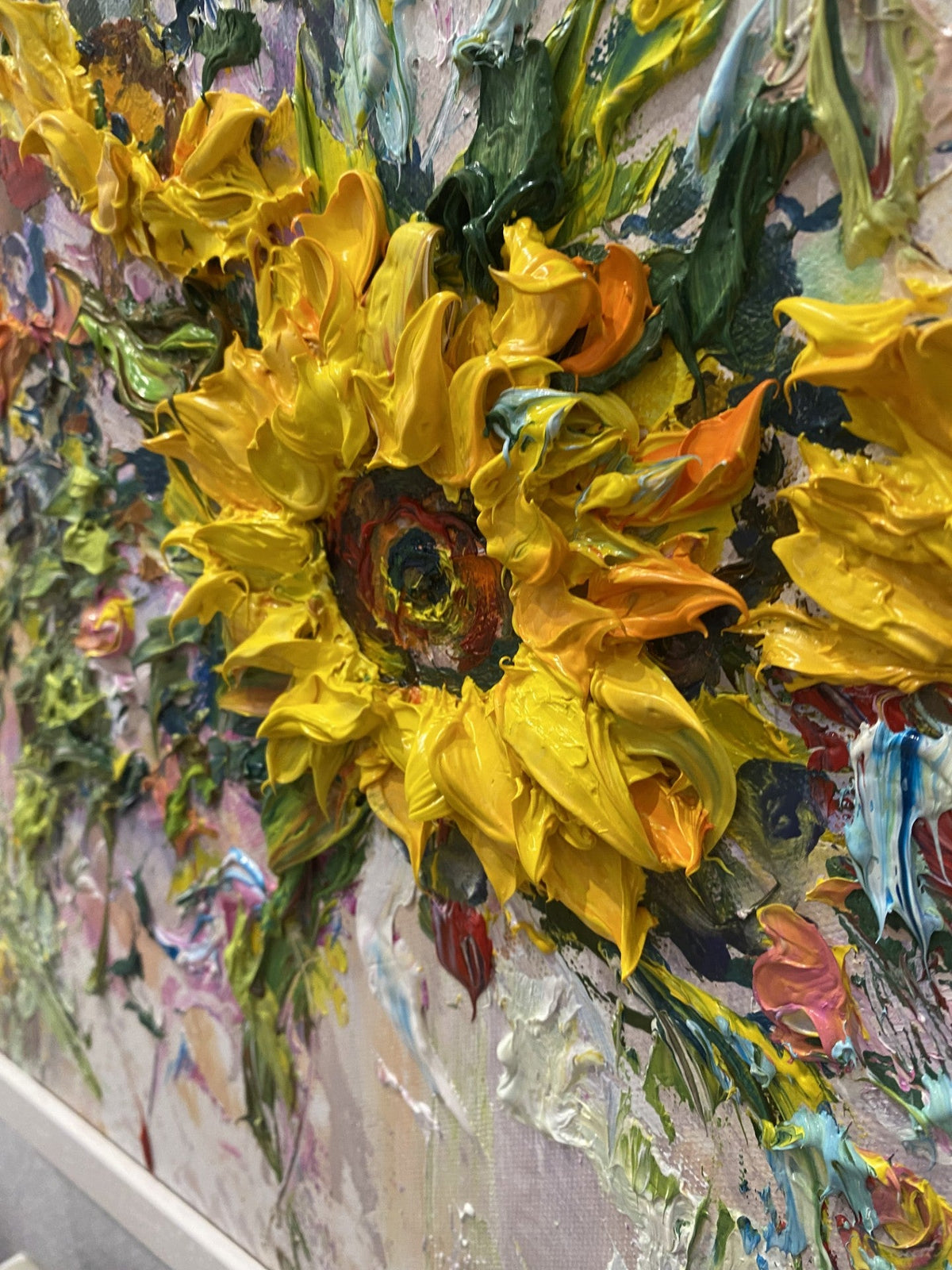 A Close Up of Radiant Resilience original painting by Yulia Lisle featuring richly textured yellow sunflowers surrounded by colourful flowers and foliage in a white frame.
